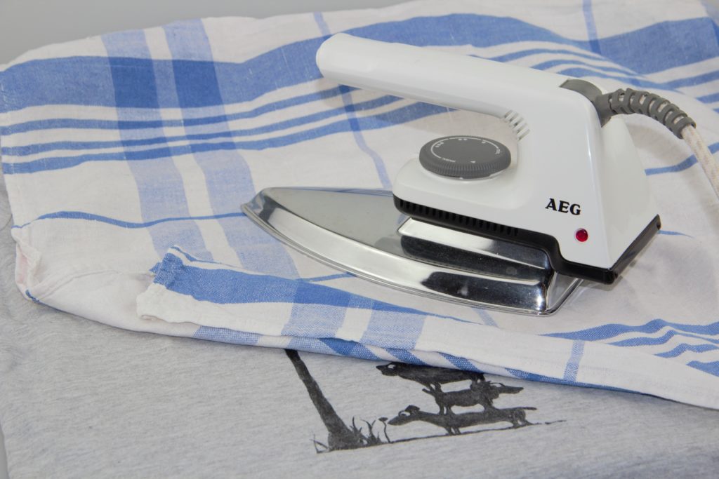Mit Textilfarbe gemaltes Motiv auf einem T-Shirt mit einem Baumwolltuch dazwischen bügeln, um die Stoffmalfarbe zu fixieren.